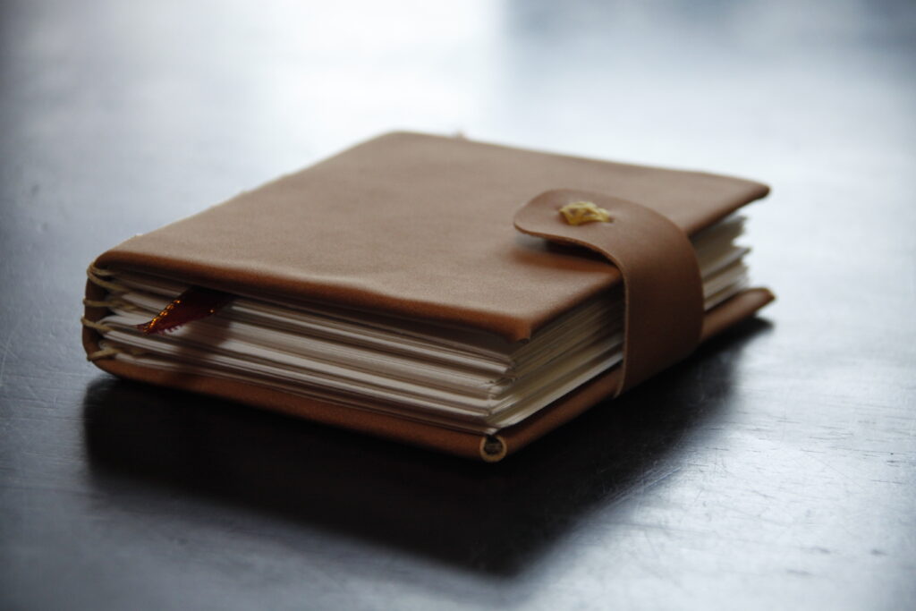 A leather bound hard cover sketchbook with a snap clasp buckle